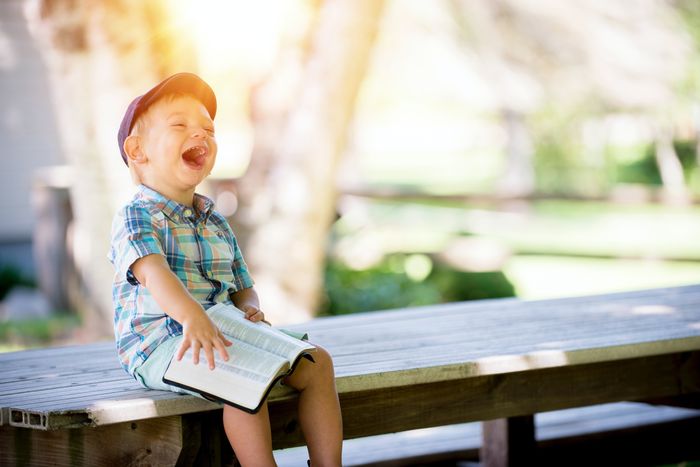 A kid sitting on a bench laughing hysterically: Photo by Ben White on Unsplash